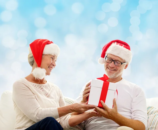 Happy senior couple in santa hats with gift box — Stock Photo, Image