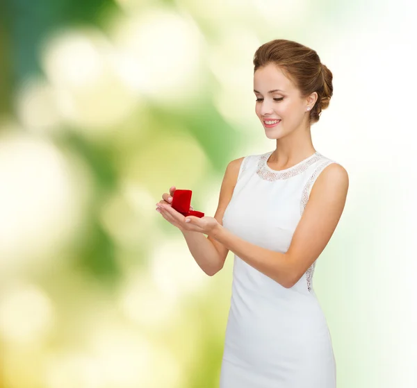 Gülümseyen kadın kırmızı hediye kutusu ile halka holding — Stok fotoğraf