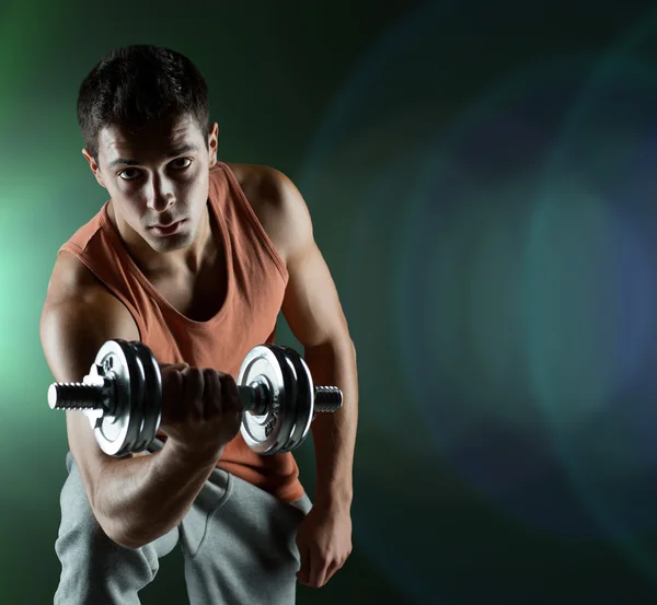 Young man with dumbbell flexing biceps — Stock Photo, Image