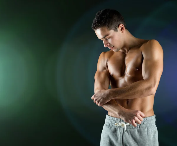 Young male bodybuilder injured touching elbow — Stock Photo, Image