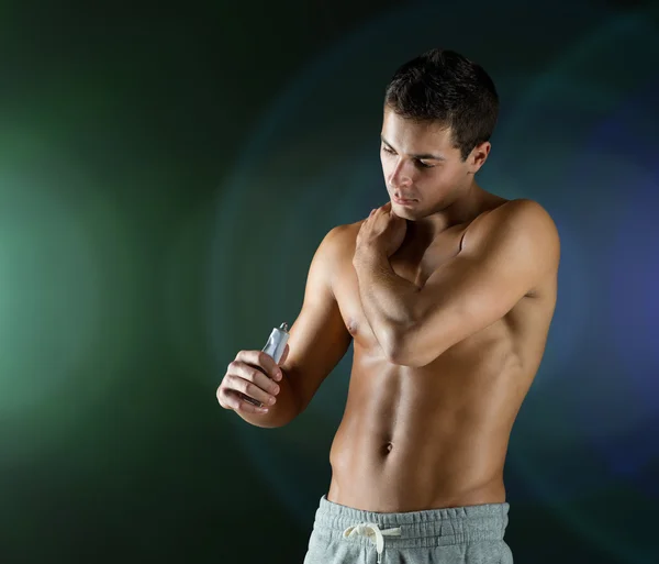 Young male bodybuilder applying pain relief gel — Stock Photo, Image