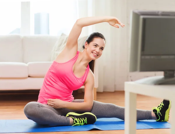 Usmíval se dospívající dívka streching na podlaze doma — Stock fotografie