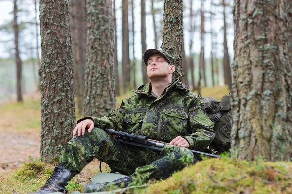 Soldier or hunter with gun sleeping in forest — Stock Photo, Image