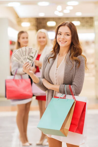 年轻女性的购物袋和金钱在购物中心 — 图库照片