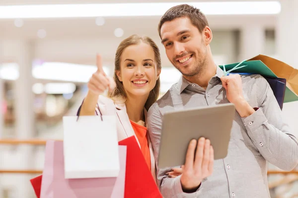 Couple with tablet pc and shopping bags in mall — Stock Photo, Image