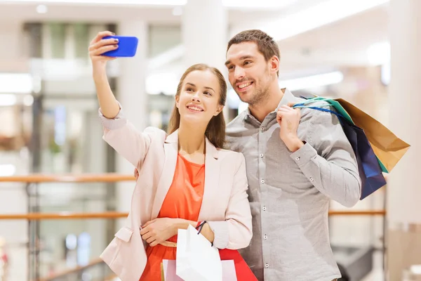 Счастливая пара со смартфоном, делающая селфи в торговом центре — стоковое фото