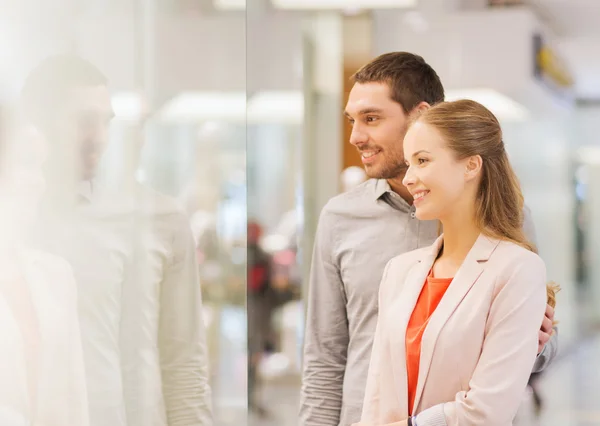 Happy couple looking to shop window in mall — Stock Photo, Image