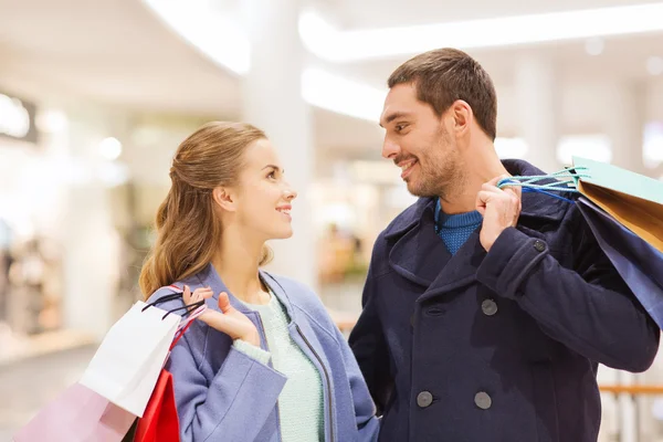 Happy young couple with shopping bags in mall — Stock Photo, Image