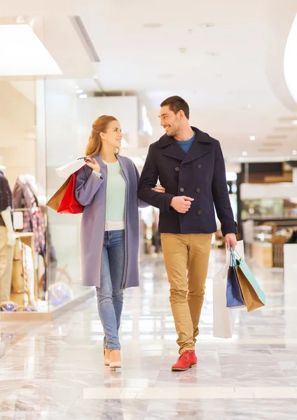 Feliz jovem casal com sacos de compras no shopping — Fotografia de Stock