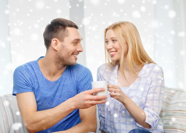 Casal sorrindo com xícara de chá ou café em casa — Fotografia de Stock