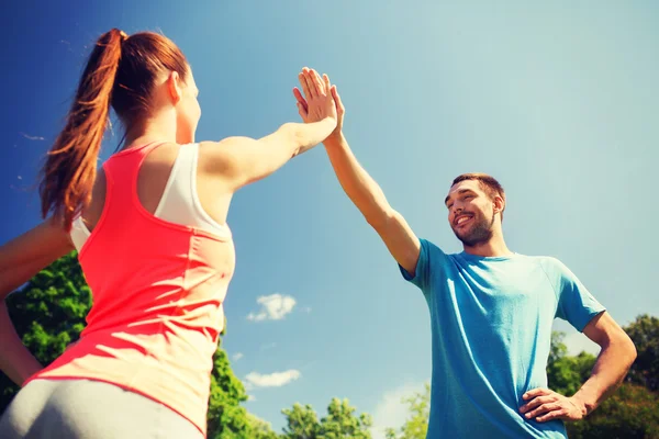 Dos personas sonrientes haciendo cinco altos al aire libre — Foto de Stock