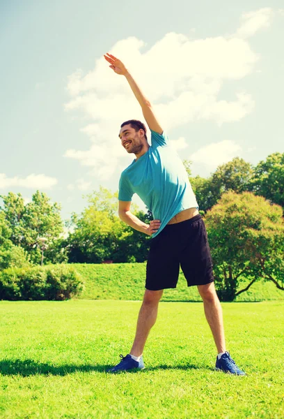 Sonriente hombre estirándose al aire libre — Foto de Stock