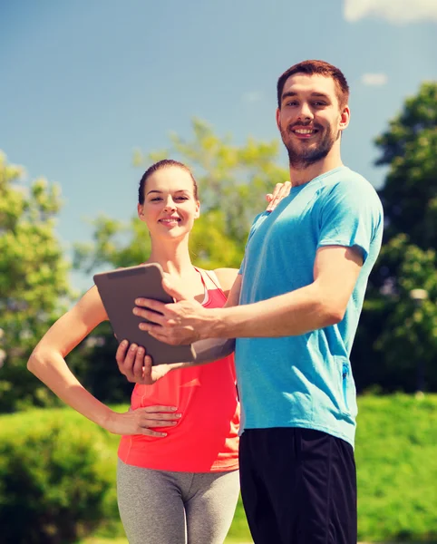 Smiling couple with tablet pc outdoors — Stock Photo, Image