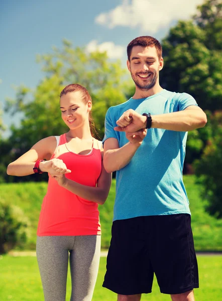 Smiling people with heart rate watches outdoors — Stock Photo, Image