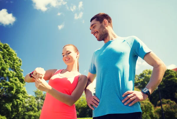 Sorridente persone con frequenza cardiaca orologi all'aperto — Foto Stock