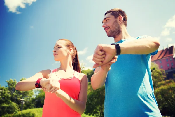 Lächelnde Menschen mit Pulsuhren im Freien — Stockfoto