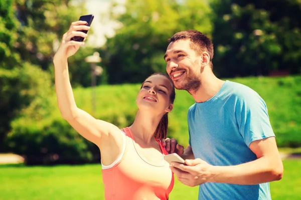 Dwa uśmiechający się ludzie z zewnątrz smartfonów — Zdjęcie stockowe