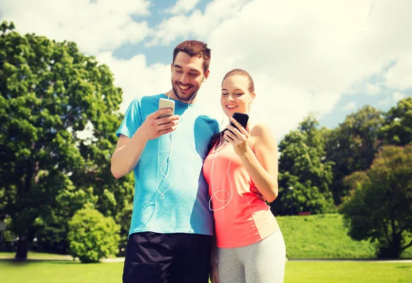 Duas pessoas sorridentes com smartphones ao ar livre — Fotografia de Stock