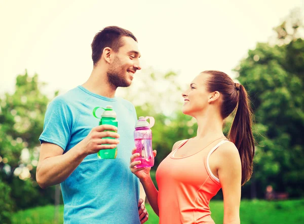 Couple souriant avec des bouteilles d'eau à l'extérieur — Photo