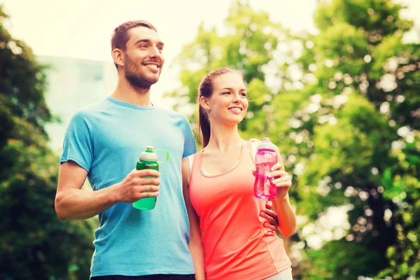 Couple souriant avec des bouteilles d'eau à l'extérieur — Photo