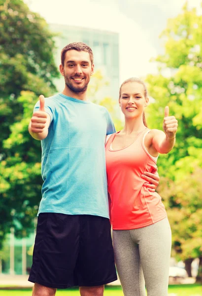 Sonriente pareja mostrando pulgares arriba al aire libre — Foto de Stock