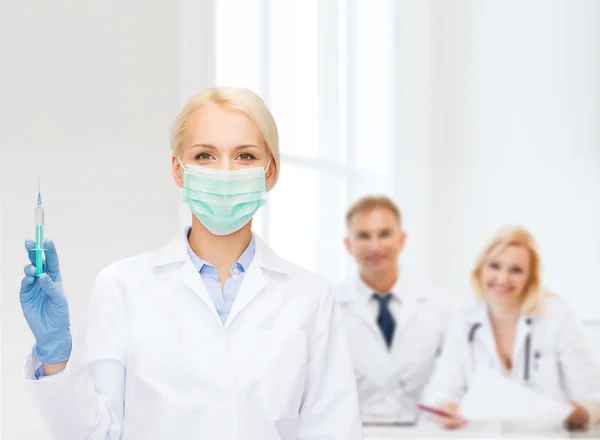 Médico con mascarilla que sostiene la jeringa con inyección —  Fotos de Stock