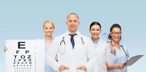 Grupp leende läkare med öga diagram — Stockfoto