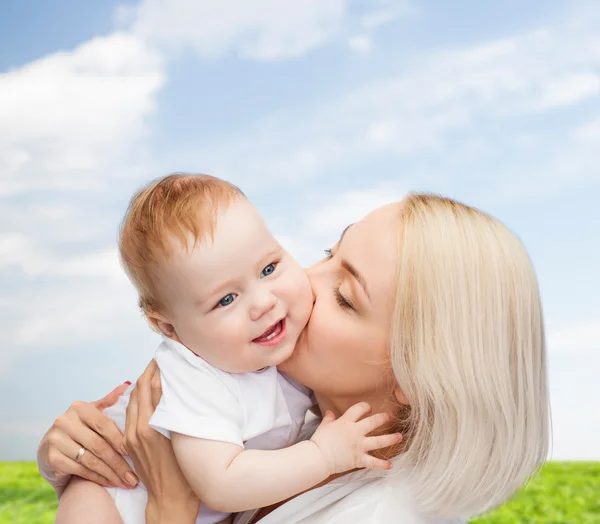 Glückliche Mutter küsst lächelndes Baby — Stockfoto