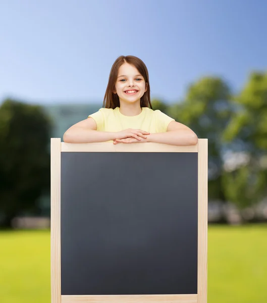 Happy little girl with blank blackboard — Stock Photo, Image