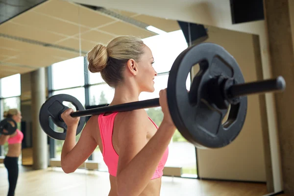 Sportliche Frau trainiert mit Langhantel im Fitnessstudio — Stockfoto