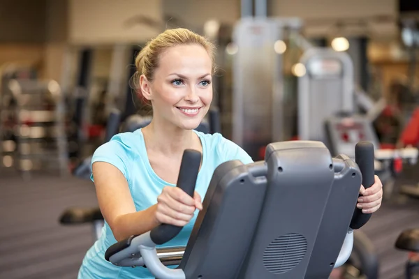 Mujer sonriente haciendo ejercicio en bicicleta estática en el gimnasio — Foto de Stock