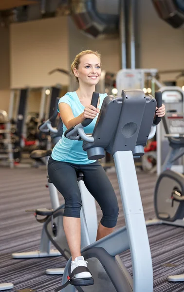 Smiling woman exercising on exercise bike in gym — Stock Photo, Image