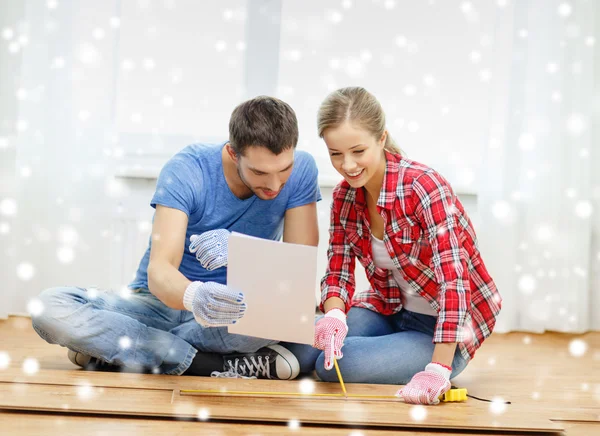 Smiling couple measuring wood flooring — Stock Photo, Image