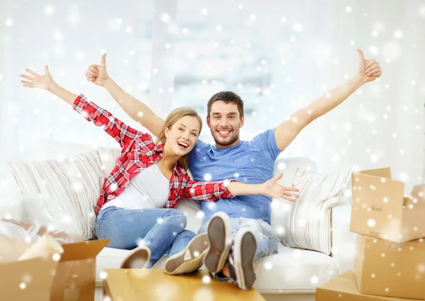 Pareja sonriente relajándose en un sofá en un nuevo hogar — Foto de Stock