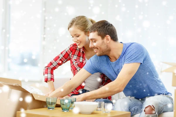 Smiling couple opening cardboard box with dishes — Stock Photo, Image