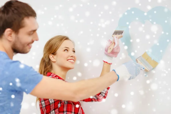 Smiling couple painting small heart on wall — Stock Photo, Image