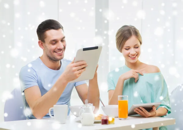 Casal sorridente com tablet pc tomando café da manhã — Fotografia de Stock