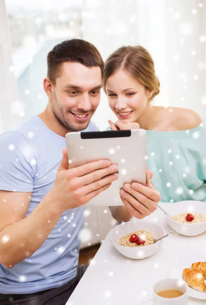 Smiling couple with tablet pc having breakfast — Stock Photo, Image