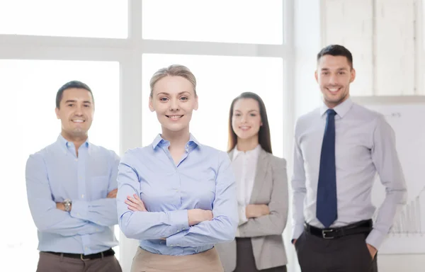 Empresária sorridente no cargo com equipe nas costas — Fotografia de Stock