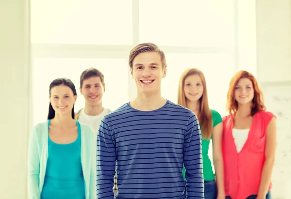 Smiling students with teenage boy in front — Stock Photo, Image