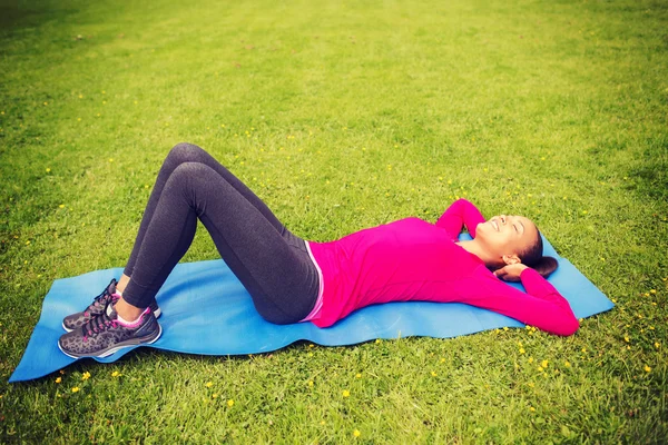 Leende kvinna gör övningar på matta utomhus — Stockfoto