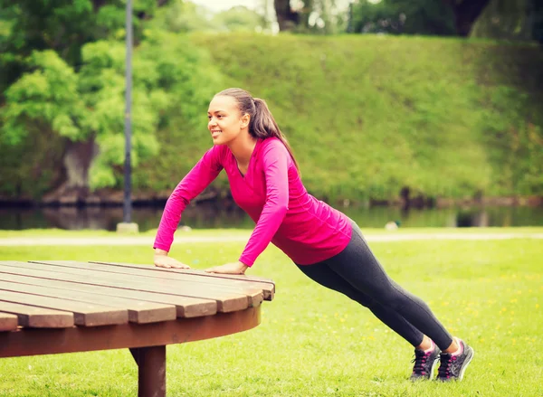 Lachende vrouw doen push-ups op Bank buitenshuis — Stockfoto