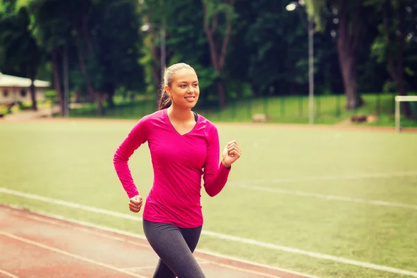 Smiling woman running on track outdoors — Stock Photo, Image