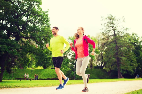 Sonriente pareja con auriculares corriendo al aire libre — Foto de Stock