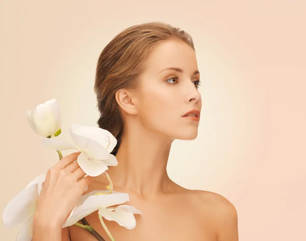 Schöne junge Frau mit Orchideenblüten — Stockfoto