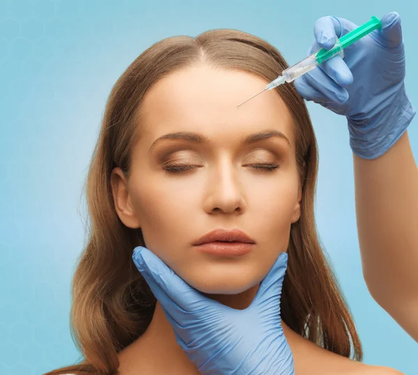 Beautiful woman face and hands with syringe — Stock Photo, Image