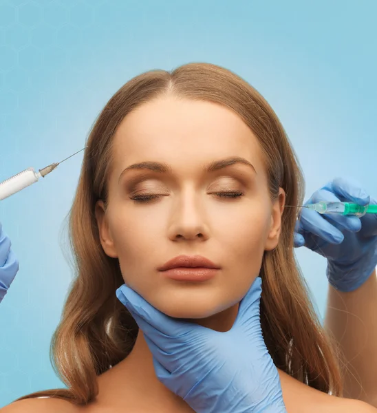 Beautiful woman face and hands with syringe — Stock Photo, Image