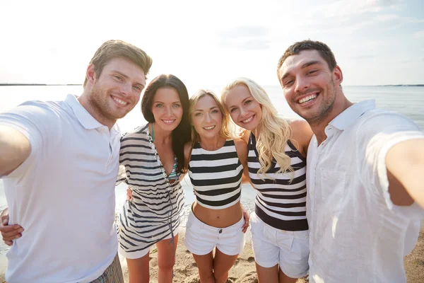 Amici felici sulla spiaggia e prendendo selfie — Foto Stock