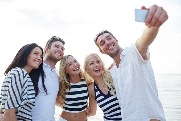 Amis heureux sur la plage et de prendre selfie — Photo