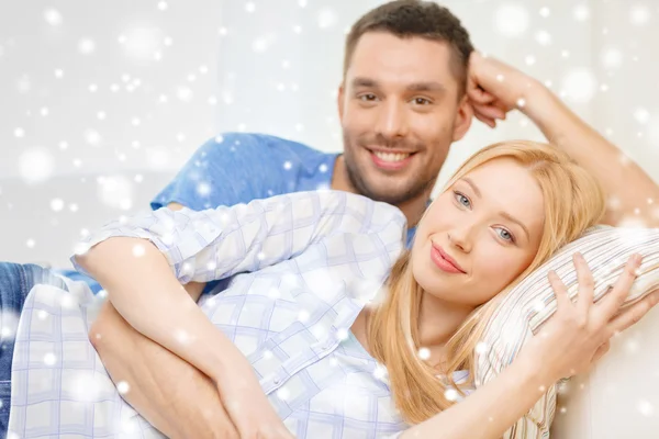 Sonriente pareja acostada en el sofá y abrazándose en casa — Foto de Stock